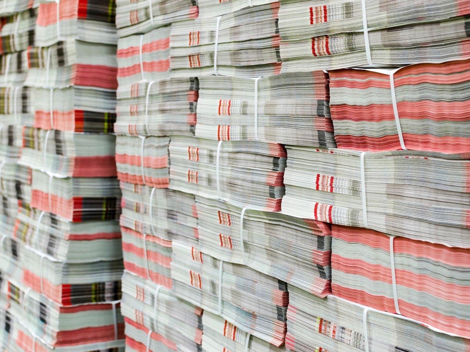 Stacked bundles of printed newspapers, strapped and ready for distribution.